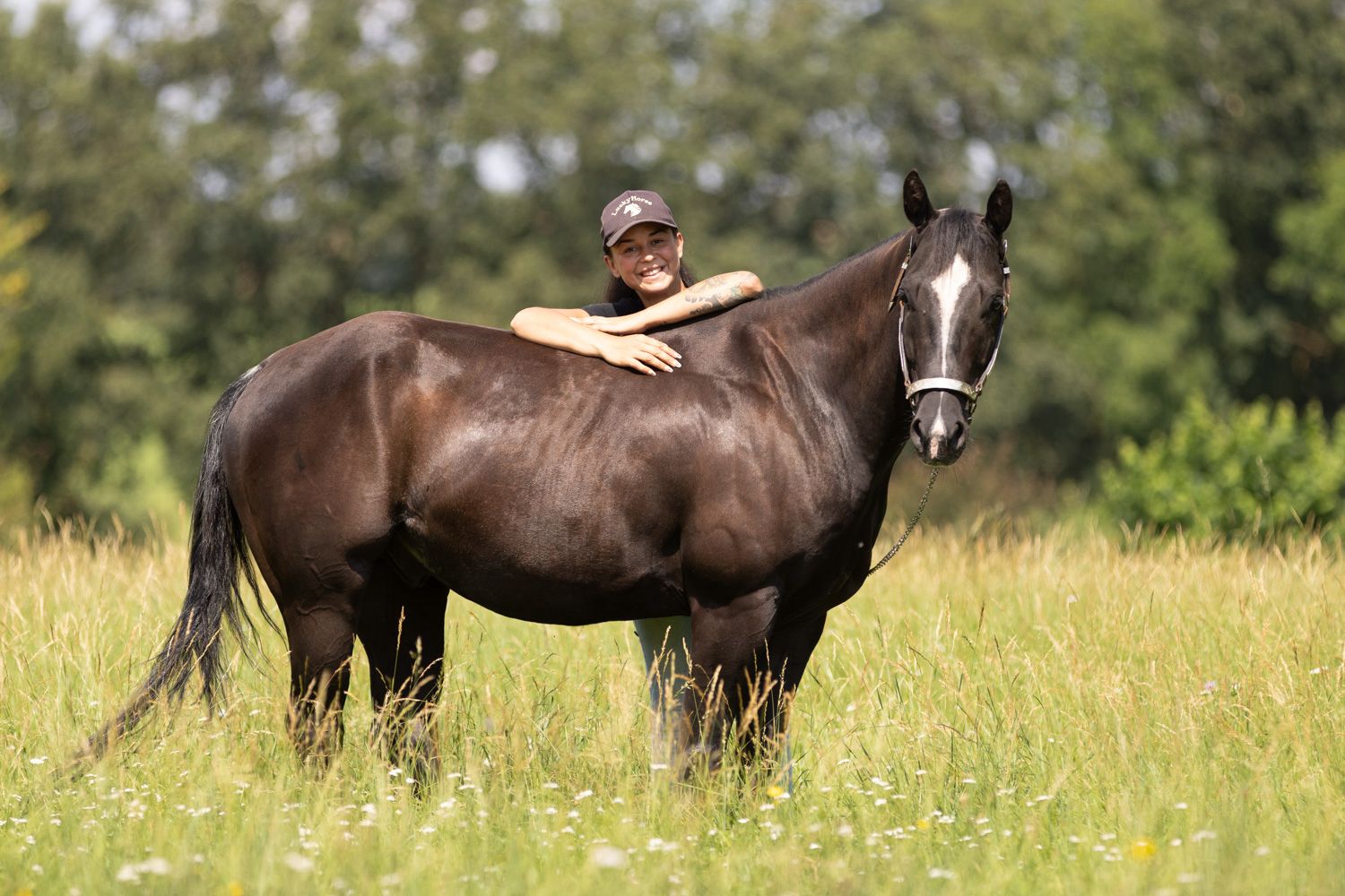 Anne Westhaus mit einem Pferd entspannt auf der Weide